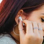 Woman putting ear-bud on ear to listen to music